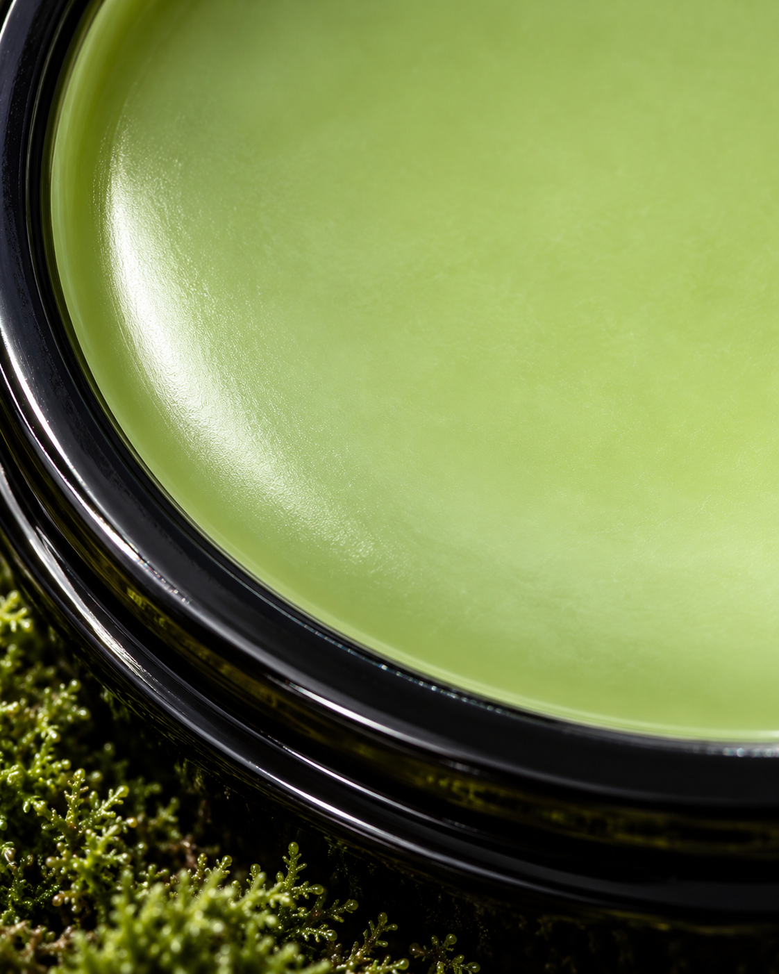 Luminous green After the Rain balm in black glass, nestled in moss