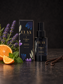 ELAA Eclipse Mist bottle and carton with citrus, mint, lavender and vanilla beans on dark stone