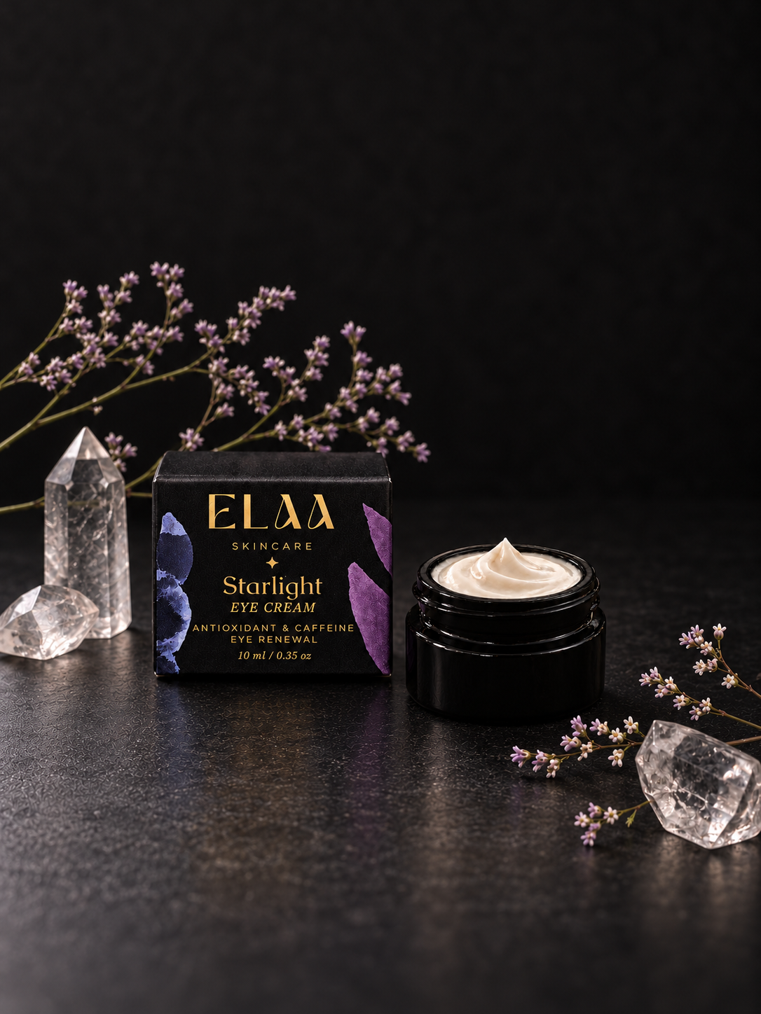 ELAA Starlight eye cream and carton with flowers and crystals on a flat dark surface